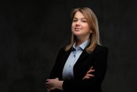 Portrait of a smiling blonde businesswoman formal dressed standing with crossed arms. Isolated on a dark textured background.